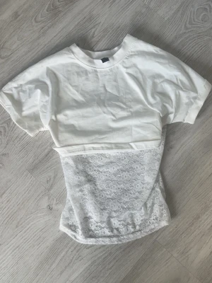 Vit croppad t-shirt med ett spetslinne - Säljer en T-shirt med ett spetslinne till som blir snyggt att ha tillsammans🤍Kolla in min profil för fler fina och trendiga plagg!