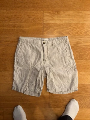 Beiga linneshorts från East West - Snygga beiga shorts i linne med klassisk passform. De har bälteshällor, knappgylf och två bakfickor med knappar. Perfekta för varma dagar och en avslappnad stil. Premium linne shorts och mina favorit shorts jag har haft.