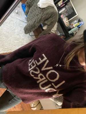Vinröd stickad tröja med text - Mysig vinröd stickad tröja med vit text 'LOVE YOURSELF' framtill. Tröjan har en avslappnad passform och rund halsringning. Perfekt för dig som gillar trendiga och bekväma plagg med budskap.