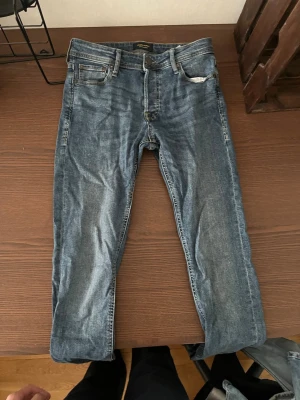 Blå jeans från Jack & Jones - Snygga blå jeans från Jack & Jones med klassisk femficksdesign och gul kontrastsöm. Jeansen har normal passform och är tillverkade i denim med lätt tvättad look. Perfekta för en avslappnad stil.