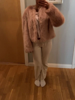 Ljusrosa fluffig pälsjacka - Säljer en supermjuk och fluffig ljusrosa pälsjacka i fuskpäls. Jackan har en kort, boxig passform med långa ärmar och rund halsringning. Jackan har aldrig använts, men tyvärr fattas prislappen. Nypris: 600kr