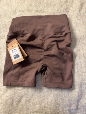 Bruna seamless shorts från Aim'n - Snygga bruna seamless shorts från Aim'n med hög midja och ribbad linning. Perfekta för träning eller chill, tillverkade i mjukt och stretchigt material som sitter skönt på kroppen. Stilren design utan synliga loggor för en clean look.