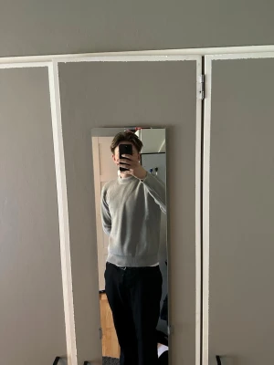 Ljusgrå ribbad tröja från Mason Margiela - Säljer en stilren ljusgrå tröja från Mason Margiela med ribbad struktur och rund hals. Tröjan har långa ärmar och en avslappnad passform, perfekt för en enkel och clean look. Passar till både jeans och kostymbyxor. Passform Medium