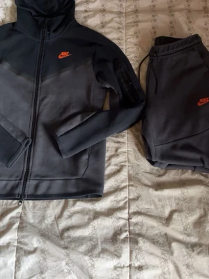 Orange svart nike tech fleece tracksuit  - Säljer en tracksuit ifrån Nike som jag har haft ett tag men har nu vuxit ur mig. Det finns absolut inga skador det är storlek S men passar mig som har storlek M går inte att få tag på längre