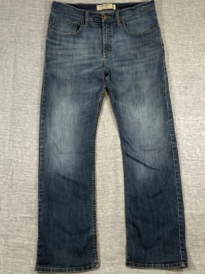 Wrangler Slim Straight Jeans Vintage Wash W34 L30 - Wrangler slim straight jeans in a clean vintage blue wash with natural fading. Easy everyday pair with slight stretch and a nice straight leg fit.  Measurements (laid flat): waist 43 cm, inseam 73 cm, rise 27 cm, thigh 29 cm, knee 22 cm, leg opening 20 cm.  Used condition, normal wear.