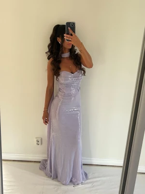 Exklusiv pastellila festklänning – XS - Säljer denna trendiga & otroligt fina festklänning i  pastellila nyans som verkligen drar blickarna till sig 💜                      💜Storlek XS (lätt insydd för en mer figurnära silhuett).   Stretchigt material som formar kroppen perfekt. Inbyggda kupor ger fint lyft utan BH. Diskret dragkedja baktill, avtagbar sjal och lång, följsam modell med släp. Sitter som en dröm och framhäver figuren exklusivt.  Perfekt för bal, gala eller speciella tillfällen ✨✨✨ Endast använd en kväll, i nyskick.