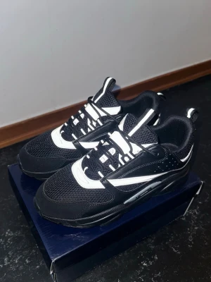 B22 sneakers svarta  - Snygga svarta sneakers från Nike med vita detaljer och mesh-paneler för extra ventilation. Skorna har klassisk låg profil, robust sula och cool design med vita swoosh-loggor på sidorna. Perfekta för dig som vill ha en sportig och trendig look.