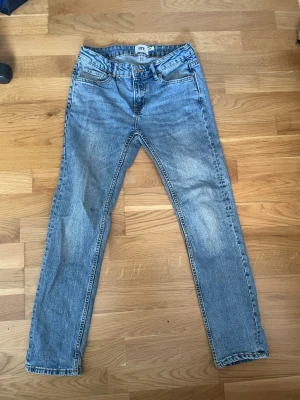 Ljusblå slimmy star  jeans från 157 - Säljer ett par ljusblå jeans från 157 med rak passform och klassisk femficksdesign. Jeansen har normal midja, dragkedjegylf och är tillverkade i ett slitstarkt denimtyg. Perfekta för en avslappnad och trendig look.
