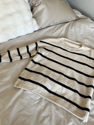 Beige stickad tröja med svarta ränder - Säljer denna beige och svart randiga stickade tröjan. Köpt på en marknad i Spanien för 400kr orginalpris. Den är mjuk och perfekt för att ha till vardags, till skolan eller till en middag💞