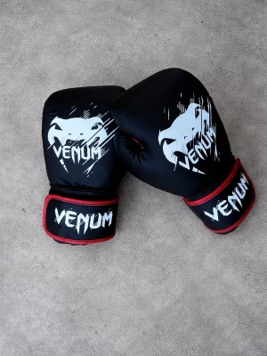 Svarta boxningshandskar från Venum - Säljer ett par svarta boxningshandskar från Venum med vit logga och coolt tryck. Insidan är röd och handskarna har bred kardborrestängning för extra stöd. Perfekta för boxning eller träning på gymmet.