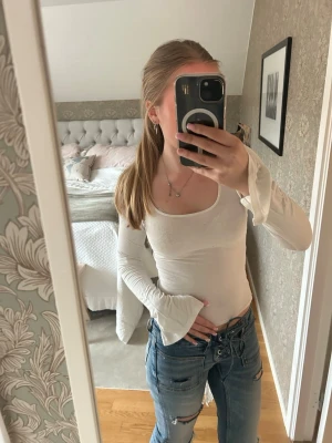 Vit tajt långärmad från Gina Tricot - Säljer en jättefin tajt vit långärmad tröja från Gina tricot i bra skick, använt den ett fåtal gånger och tröjan är i mjukt tyg med slits på båda ärmar, urringning och en snygg passform! I storlek XS