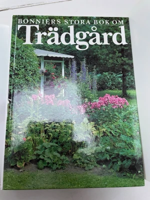 Bonniers stora bok om trädgård - En inspirerande och informativ bok om trädgårdsskötsel från Bonnier. Omslaget har ett färgstarkt foto av en lummig trädgård med blommor och gröna växter. Boken har hårda pärmar och är perfekt för dig som vill lära dig mer om växter och trädgårdsdesign.