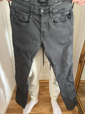 Gråa Replay Hyperflex jeans - Säljer ett par gråa Replay Hyperflex jeans med slim fit och klassisk femficksdesign. Jeansen har stretchigt material för extra komfort och en snygg tvättad look. Märkeslapp bak i midjan och diskret Replay-logga vid fickan.