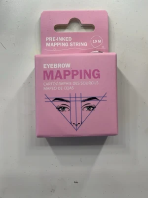 Pre-inked mapping string för bryn - Rosa förpackning med pre-inked mapping string för ögonbryn, 10 meter. Perfekt för att markera och forma bryn med precision. Lätt att använda vid brynstyling och microblading. Kommer i en kompakt kartong med grafiskt tryck.