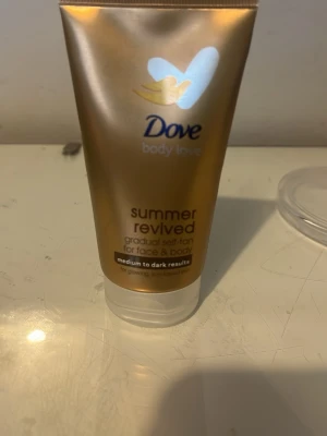 Dove Summer Revived Brun utan sol - Dove Summer Revived är en brun utan sol-lotion för ansikte och kropp. Ger gradvis solkysst ton, passar medium till mörk hudton. Tuben är guldig med vit kork och rymmer 75 ml. Innehåller aloe vera och vitamin E för återfuktning. Mini och har lite mer än hälften kvar. 