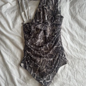  boddy I ormmönster -  säljer den här super fina body i ormmönster. Säljer på grund av att den aldrig Kommit till användning den är helt ny med prislapp pris kan diskuteras!