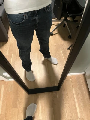 Mörkblå raka jeans - Säljer ett par klassiska mörkblå jeans med rak passform och fem fickor. Jeansen har subtila slitningar och kontrastsömmar. Perfekta till en avslappnad stil och tillverkade i slitstarkt denimtyg.