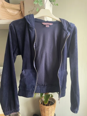 Mörkblå hoodie från Hunkemöller - Säljer en mörkblå hoodie från Hunkemöller i storlek XS. Hoodien har dragkedja, två fickor framtill och en huva. Materialet är mjukt och känns som velour, perfekt för en chill look. Passar dig som gillar bekväma och stilrena plagg. Har dock lite vit färg på sig, men de försvinner i tvätt, Vill du ha den tvättad skriv!🥰