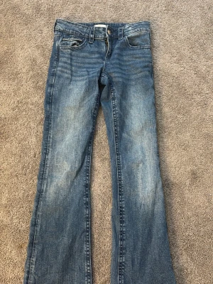Blå bootcut jeans med broderade fickor - Bootcut jeans från Gina storlek 164. Saknas en knapp på ena bakfickan.