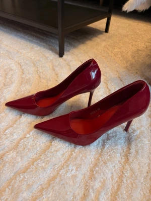 Vinröda lackpumps med spetsig tå - Säljer ett par vinröda pumps i glansigt lackmaterial med spetsig tå och smal hög klack. Skorna har en elegant och klassisk design som passar perfekt till många olika outfits. Storlek 39. Använd 1 gång endast 