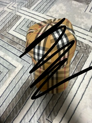 Rutig keps i klassiskt mönster - Snygg keps med rutigt mönster i beige, svart, vitt och rött. Kepsen har böjd skärm och justerbar baksida. Perfekt accessoar för en trendig streetstyle-look.