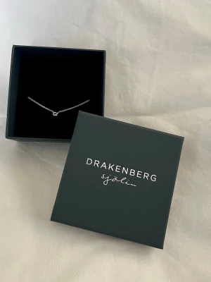 Äkta Silver halsband Drakenberg Sjölin - Ett stilrent halsband i äkta 925 stämplat silver från Drakenberg Sjölin. Kedjan är tunn och elegant. Dekorerad med den klassiska knopen. Perfekt för dig som gillar minimalistiska smycken och vill ha något diskret men ändå unikt. Levereras i originalask och är ny med plombering/prislapp 