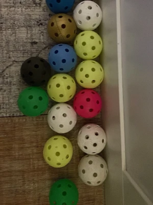 Färgglada innebandybollar mix - Säljer ett gäng innebandybollar i olika färger som vit, blå, grön, gul, rosa, brun och svart. Bollarna är tillverkade i plast och har klassiska hål runt om. Perfekt för träning eller spontanspel med kompisarna.