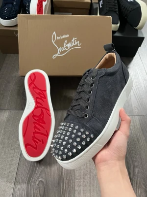 Christian Louboutin svarta sneakers - Snygga svart/ gråa sneakers från Christian Louboutin i mocka med ikoniska röda sulor och silverfärgade nitar på tån🤩 Storlek 40 i toppen skick😇 Hör av er vid funderingar samt snabbaffär🙌🏻