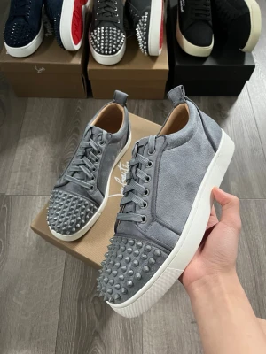 Gråa Christian Louboutin sneakers - Snygga gråa sneakers från Christian Louboutin i mocka med ikoniska nitar på tån och vita sulor🤩 Storlek 42 fint skick🙌🏻 Pris ej hugget i sten och hör av er vid funderingar😇
