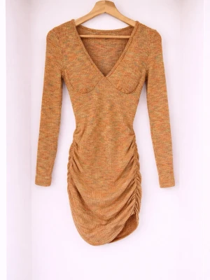 Beige ribbad kortklänning med v-ringning - Trendig beige kortklänning med ribbad struktur och v-ringad hals. Klänningen har långa ärmar, åtsittande passform och snygga rynkade detaljer längs sidorna. Perfekt för dig som gillar en modern och stilren look.