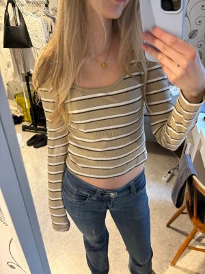 Beige och vit randig ribbad topp - Topp i beige med vita och bruna ränder i storlek S. Toppen är ribbad, har lång ärm och en rundad halsringning💗