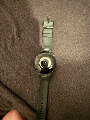 Svart Samsung Galaxy Watch - Snygg svart Samsung Galaxy Watch med rund urtavla och silikonarmband. Klockan har en stilren design och passar perfekt för dig som vill ha koll på både träning och notiser direkt på handleden. Materialet är en mix av metall och silikon för bekväm användning. Original laddare samt box finns kvar. Priset kan diskuteras