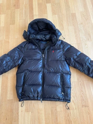 Svart dunjacka från Polo Ralph Lauren - Snygg svart dunjacka från Polo Ralph Lauren. Använd sparsamt o i väldigt bra skick. Storlek L. Äkta och bra kvalitet. Hör av er vid prisförslag!