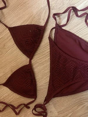 Vinröd virkad bikini från Waikani - Supersnygg vinröd bikini från Waikani i virkad stil. Bikinin har trekantsmodell på överdelen och knytband både upptill och nedtill. Materialet känns mjukt och bekvämt, perfekt för lata dagar på stranden.