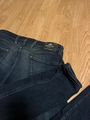 Mörkblå skinny jeans från Replay - Snygga mörkblå jeans från Replay med klassisk femficksdesign och diskreta slitningar. Jeansen har en smal passform och är tillverkade i stretchigt denim för extra komfort. Perfekta för en trendig och avslappnad look.