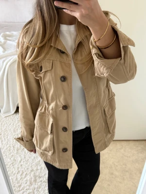 Beige vårjacka - Säljer en snygg beige jacka från KappAhl i storlek XS. Midjan går att justera. Superfint skick!