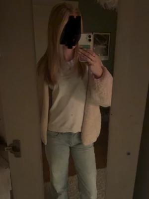 Beige fluffig kofta öppen modell - Säljer en beige, fluffig kofta i öppen modell med lång ärm. Koftan har en avslappnad passform och är gjord i ett mjukt material som ger en cozy vibe. Perfekt att slänga över en t-shirt för en chill look.