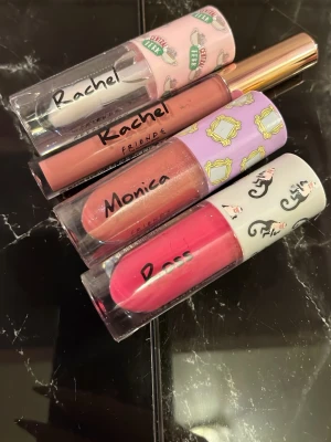 Friends läppglans-set Rachel Monica Ross - Säljer ett set med tre läppglans från Friends-kollektionen. Färgerna är nude (Rachel), skimrande persika (Monica) och stark rosa (Ross). Förpackningarna har gulliga motiv och karaktärernas namn tryckta på locket. Perfekt för dig som älskar färg och popkultur!