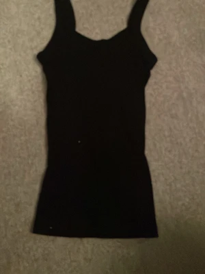 Svart linnetopp från Gina Tricot - En enkel och stilren svart linnetopp från Gina Tricot, perfekt för lager på lager eller att bära som den är. Toppen har breda axelband och en rak passform som gör den lätt att matcha med olika outfits. Nypris ungefär 129kr. Mitt pris 50kr.