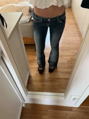 Blå bootcut jeans med broderi - Säljer ett par blå bootcut jeans med snygga fickor. Lågmidjade och något slitna längst ned vid fötterna. Storleken är M men jag skulle säga att dom passar för S mer💞💞
