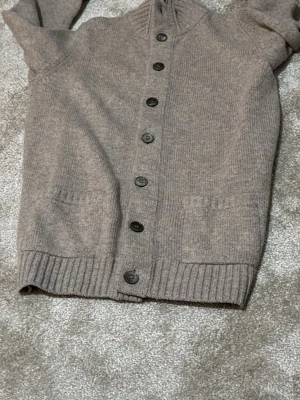 Beige stickad kofta med knappar Alan paine - Mysig beige stickad kofta med långa ärmar och ribbade muddar.  Perfekt för lager på lager, passar utmärker med en skjorta under märke Alan paine, storlek 46 vilket motsvarar S