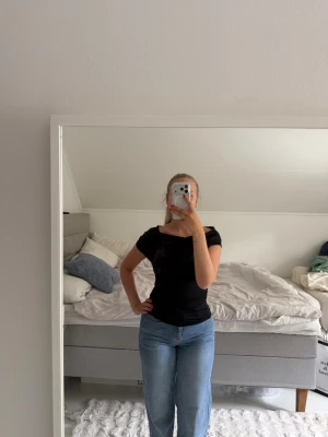 Svart offshoulder topp - Säljer en svart offshoulder topp med tight passform. Toppen har korta ärmar och en stilren, enkel design som passar till mycket. Perfekt att matcha med jeans eller kjol för en snygg look.