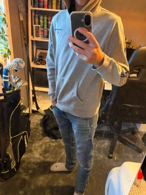 Grå hoodie från Polo Ralph lauren  Sport - Snygg grå hoodie från Polo Sport med huva och magficka. Diskret Polo Sport-logga med amerikansk flagga på bröstet och tryck på ena ärmen. Tillverkad i mjukt bomullsmaterial, perfekt för en chill och avslappnad stil. Konstig storlek men passar vuxen XS