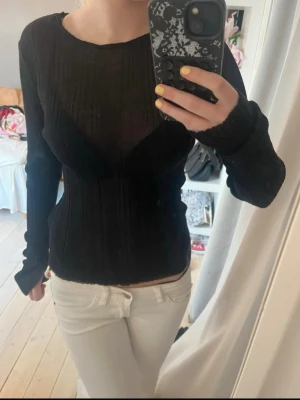 Svart ribbad långärmad tröja - Säljer en svart, figurnära långärmad tröja med ribbad struktur och rund halsringning. Tröjan har en stilren och enkel design som passar perfekt till jeans eller kjol. 