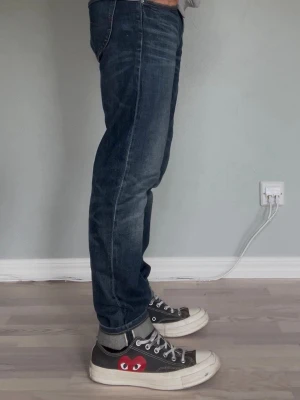 Lee Jeans – Vintage H.D. Lee | Mörkblå | Straight Fit - LEE JEANS — H.D. LEE MERC. COMPANY  Märke: Lee Passform: Straight fit Färg: Mörkblå med naturlig fading Storlek: W30 och L30                                         Sitter snyggt längs benet — varken för tajt eller för baggy. En pålitlig, tidlös jean som funkar till det mesta.  Modellen på bilden är 175cm och väger 65 kg.  Skick: Mycket bra skick utan defekter. Nypris: ca 900 SEK
