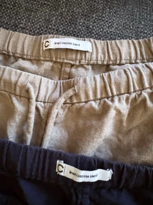 Två par linneshorts  i beige och svart - Säljer två par linnebyxor från C i färgerna beige och svart. Båda har resår i midjan och dragsko för skön passform. Tillverkade i en mjuk blandning av linne och viskos som känns luftigt och svalt. Perfekta för en avslappnad stil.