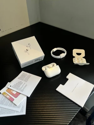 Apple AirPods Pro med laddningsetui - Säljer ett par vita Apple AirPods Pro med trådlöst laddningsetui. Hörlurarna har en stilren och kompakt design, silikonpluggar i olika storlekar och levereras med originalkartong, laddkabel och manualer. Perfekta för dig som vill ha grymt ljud och smidig anslutning till din iPhone. HELT NY!!