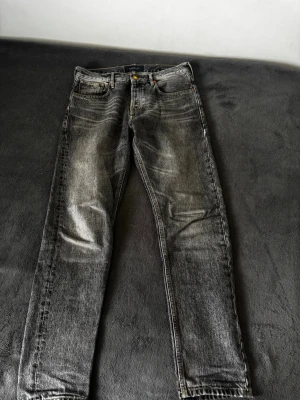 Grå regular jeans - Säljer ett par grå regular fit jeans med tvättad look. Klassisk femficksdesign och raka ben. Perfekt för dig som gillar en avslappnad och trendig stil. Materialet är denim och jeansen har en snygg faded effekt.