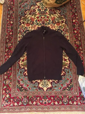 Mörkblå ziptröja med hög krage - Säljer en stilren mörklila ziptröja med hög krage och långa ärmar. Tröjan har hel dragkedja framtill och ribbade muddar vid ärmslut och nederkant. Perfekt för lager på lager och enkel att matcha med olika outfits.