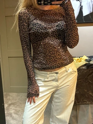 Leopardmönstrad mesh topp - Säljer en långärmad, tight mesh topp med leopardmönster. Toppen har en brun och svart färgskala och är tillverkad i ett tunt, stretchigt syntetmaterial. Står ej storlek men runt s-m